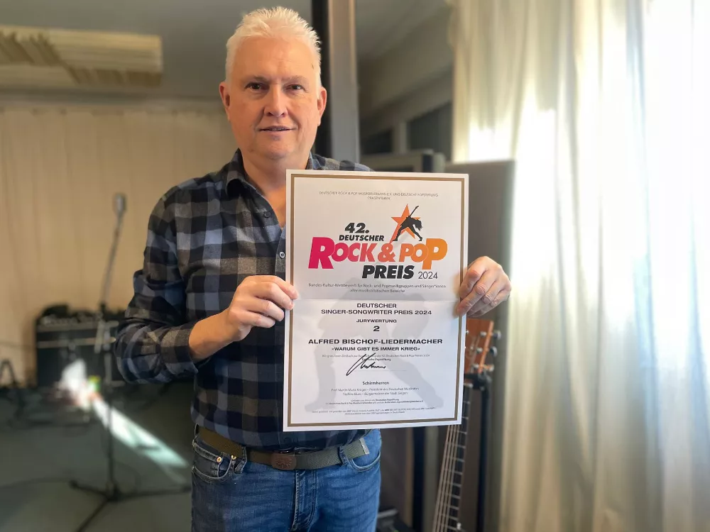 Ausgezeichnet als Singer-Songwriter: Alfred Bischof mit seiner zweiten Urkunde beim Deutschen Rock & Pop Preis 2024 – aufgenommen im Proberaum. Ausgezeichnet als Singer-Songwriter: Alfred Bischof mit seiner zweiten Urkunde beim Deutschen Rock & Pop Preis 2024 – aufgenommen im Proberaum.