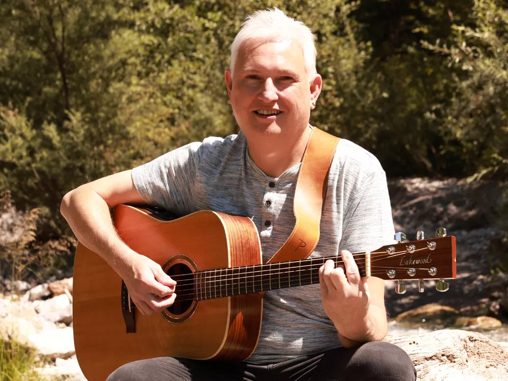 Liedermacher Alfred Bischof mit Gitarre am Bach – stiller Moment in der Natur Liedermacher Alfred Bischof mit Gitarre am Bach – stiller Moment in der Natur