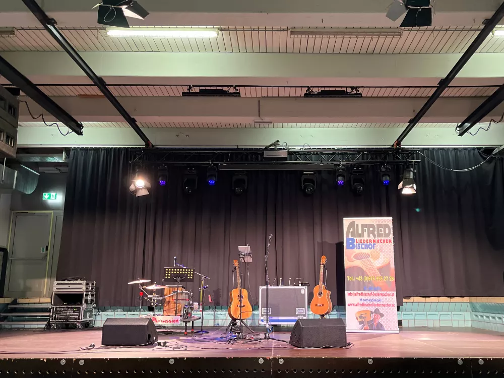 Die Bühne wartet: Leerer Saal, ruhige Atmosphäre vor Konzertbeginn im Alten Hallenbad Feldkirch – Gitarre und Technik bereit für Alfred Bischofs Auftritt 2024. Die Bühne wartet: Leerer Saal, ruhige Atmosphäre vor Konzertbeginn im Alten Hallenbad Feldkirch – Gitarre und Technik bereit für Alfred Bischofs Auftritt 2024.