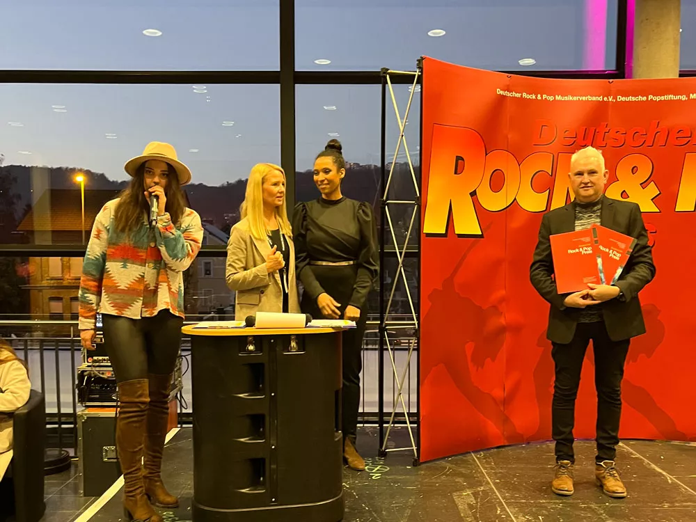 Alfred Bischof bei der Verleihung der Sonderkategorie beim Deutschen Rock & Pop Preis 2022 – gemeinsam mit den Moderatorinnen auf der Bühne, Auszeichnungen in der Hand. Alfred Bischof bei der Verleihung der Sonderkategorie beim Deutschen Rock & Pop Preis 2022 – gemeinsam mit den Moderatorinnen auf der Bühne, Auszeichnungen in der Hand.